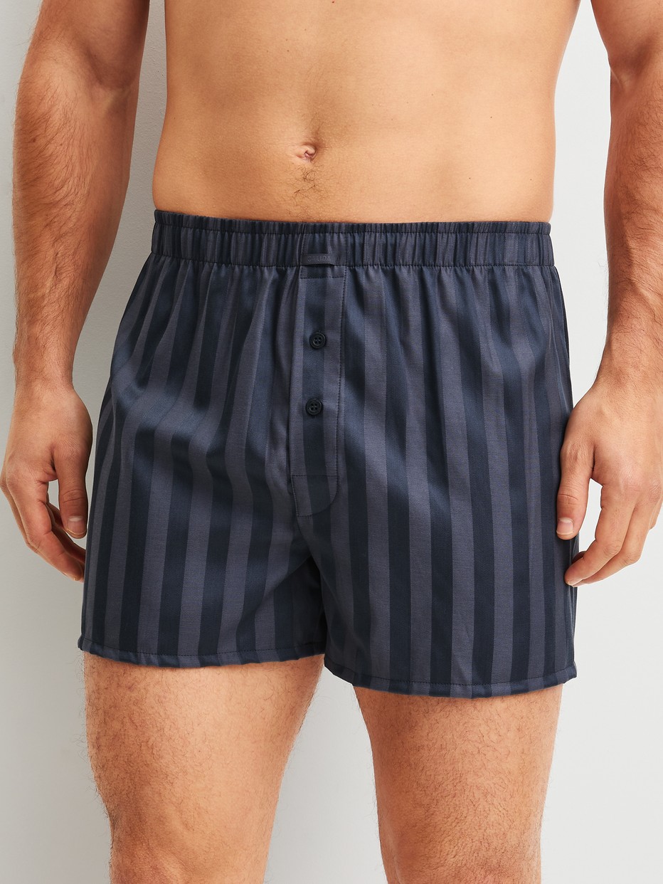 La modella / Il modello Uomo indossa Boxer short in Lyocell di colore Grigio, A righe, della serie Woven Lux di CALIDA, Vista frontale