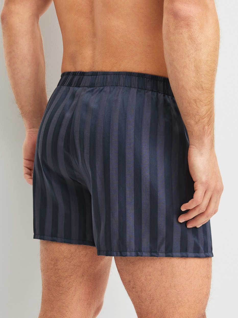 La modella / Il modello Uomo indossa Boxer short in Lyocell di colore Grigio, A righe, della serie Woven Lux di CALIDA, Vista posteriore