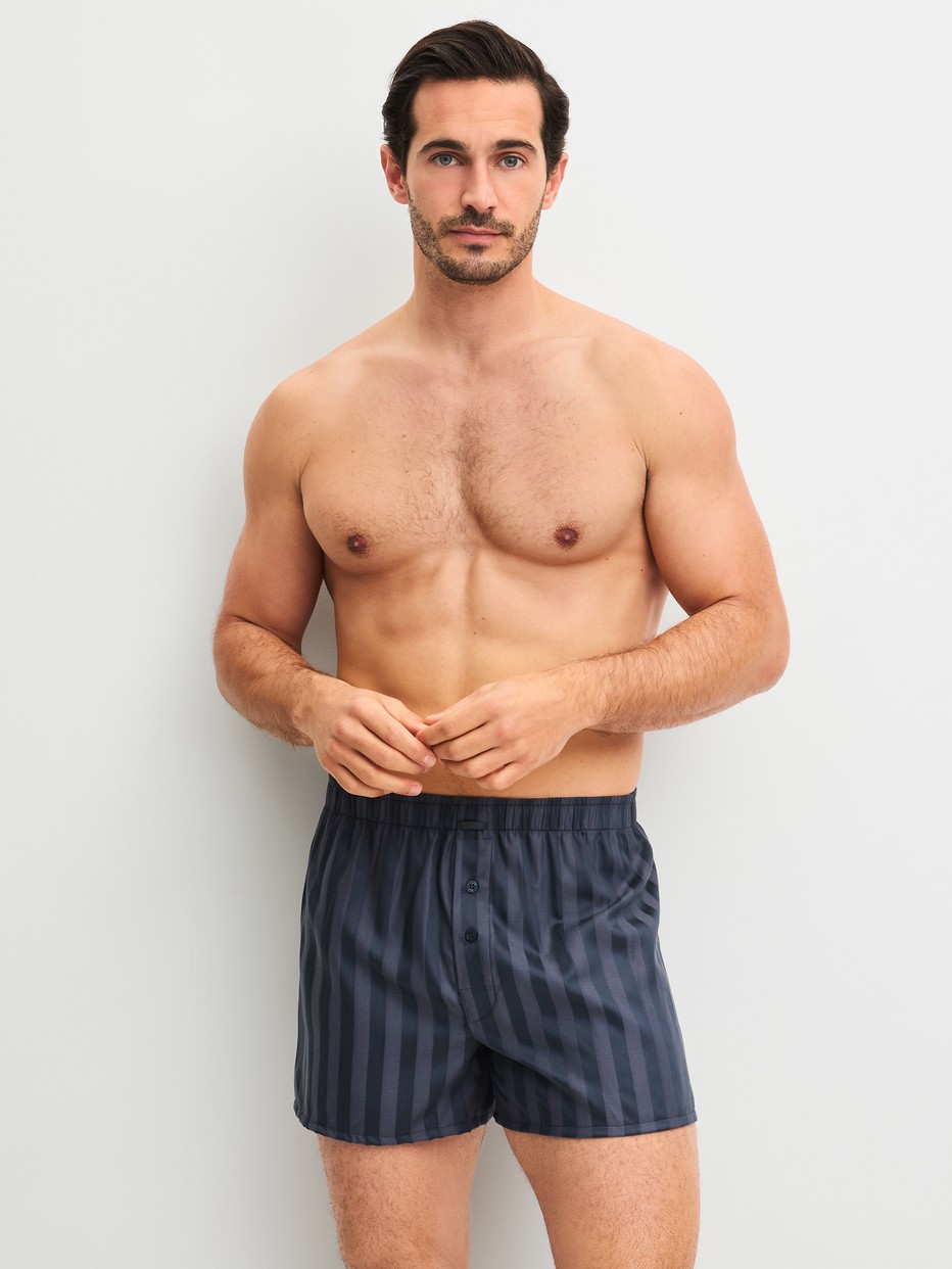 La modella / Il modello Uomo indossa Boxer short in Lyocell di colore Grigio, A righe, della serie Woven Lux di CALIDA, Abbigliamento
