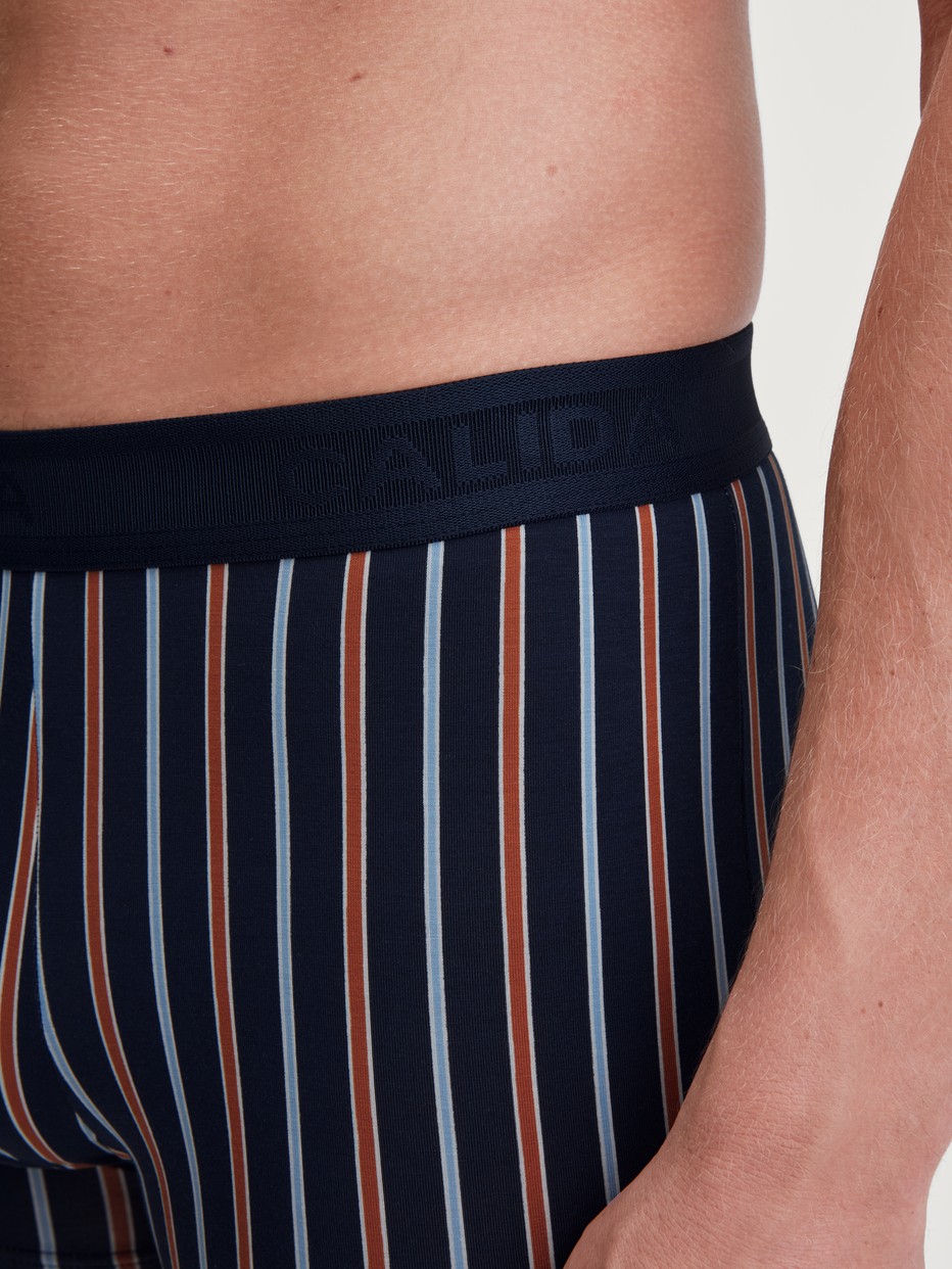 Herren-Model trägt Boxer Brief mit Softgummibund aus Baumwolle in Orange, Gemustert aus Serie Grafic Cotton von CALIDA, Detail