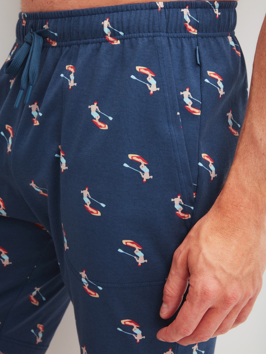 Herren-Model trägt Bermudas aus 100% Baumwolle in Blau, Gemustert aus Serie RMX Sleep Holiday von CALIDA, Detail