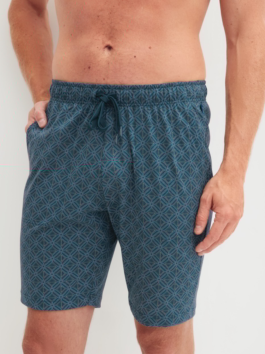 Herren-Model trägt Bermudas aus 100% Baumwolle in Türkis, Gemustert aus Serie RMX Sleep Leisure von CALIDA, Vorderansicht