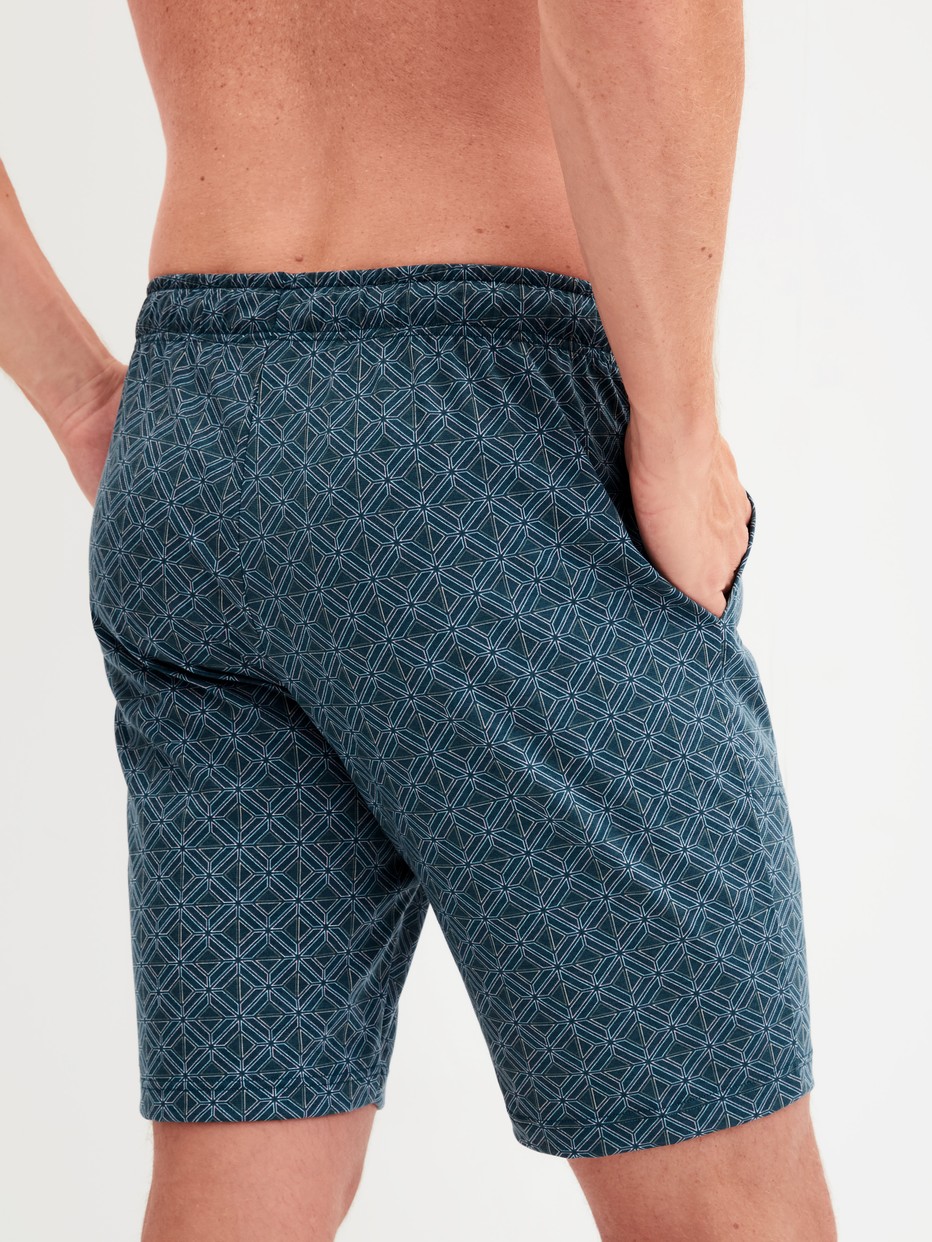 Herren-Model trägt Bermudas aus 100% Baumwolle in Türkis, Gemustert aus Serie RMX Sleep Leisure von CALIDA, Rückansicht