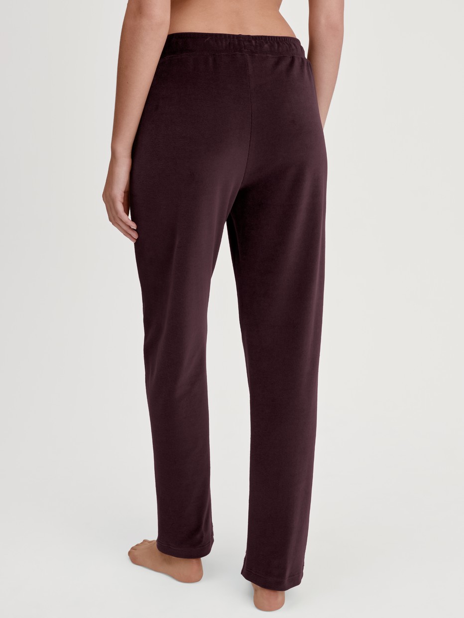 La modella / Il modello Donna indossa Pantaloni da casa in velluto in Cotone di colore Rosso, Tinta unita, della serie Lounge Velours di CALIDA, Vista posteriore