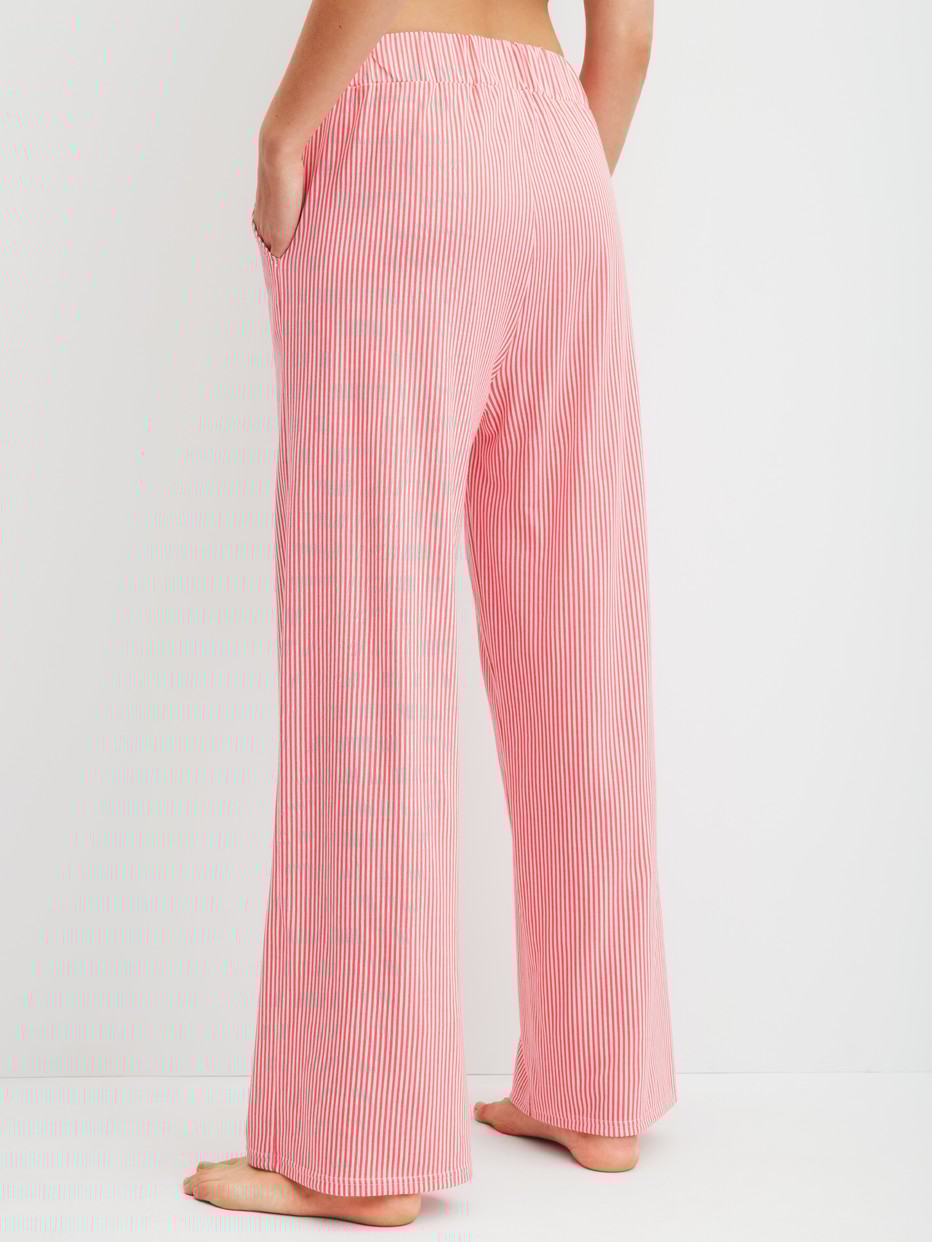 Women model is wearing Pyjama bottom made of Cotton in Orange, Striped from the Favourites Beach series by CALIDA, Back view