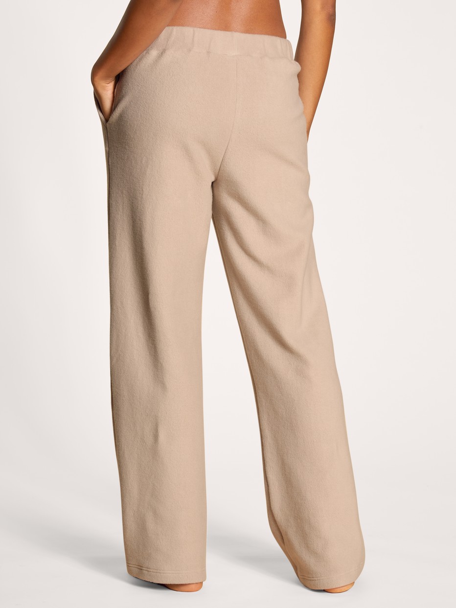 Damen-Model trägt Pants mit Seitentaschen aus Viskose in Beige, Einfarbig aus Serie The Home Hub von CALIDA, Rückansicht