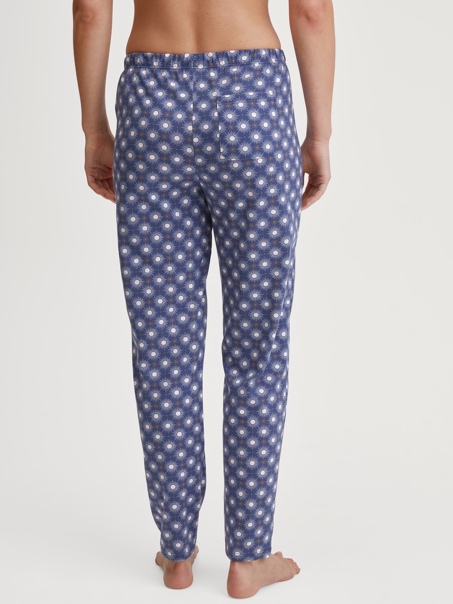 Damen-Model trägt Pyjamahose aus 100% Baumwolle in Blau, Gemustert aus Serie Favourites Universe von CALIDA, Rückansicht