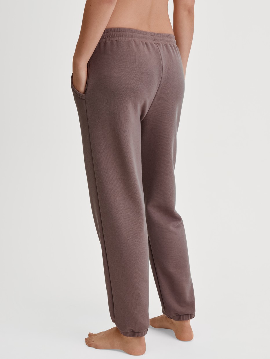 Women model is wearing Lounge Pants with Side Pockets made of Cotton in Brown, Unicoloured from the Lounge Element series by CALIDA, Back view