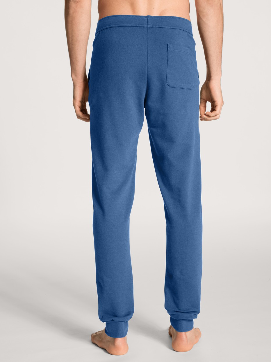 Herren-Model trägt Jogginghose mit Seitentaschen aus Baumwolle in Blau, Einfarbig aus Serie Remix Xtra von CALIDA, Rückansicht