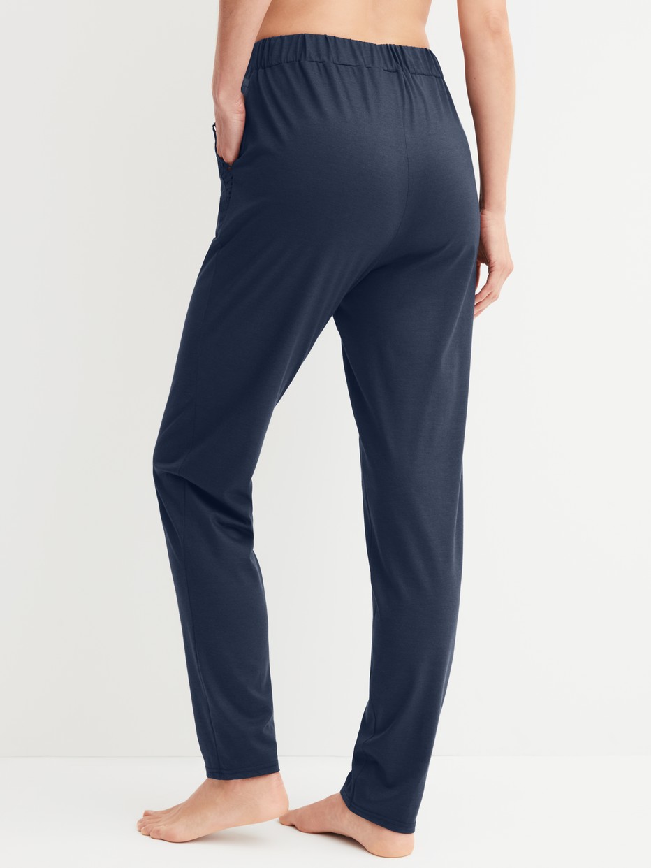 Women model is wearing Pyjama trousers with cuffs made of Cotton in Blue, Unicoloured from the Favourites Tiles series by CALIDA, Back view