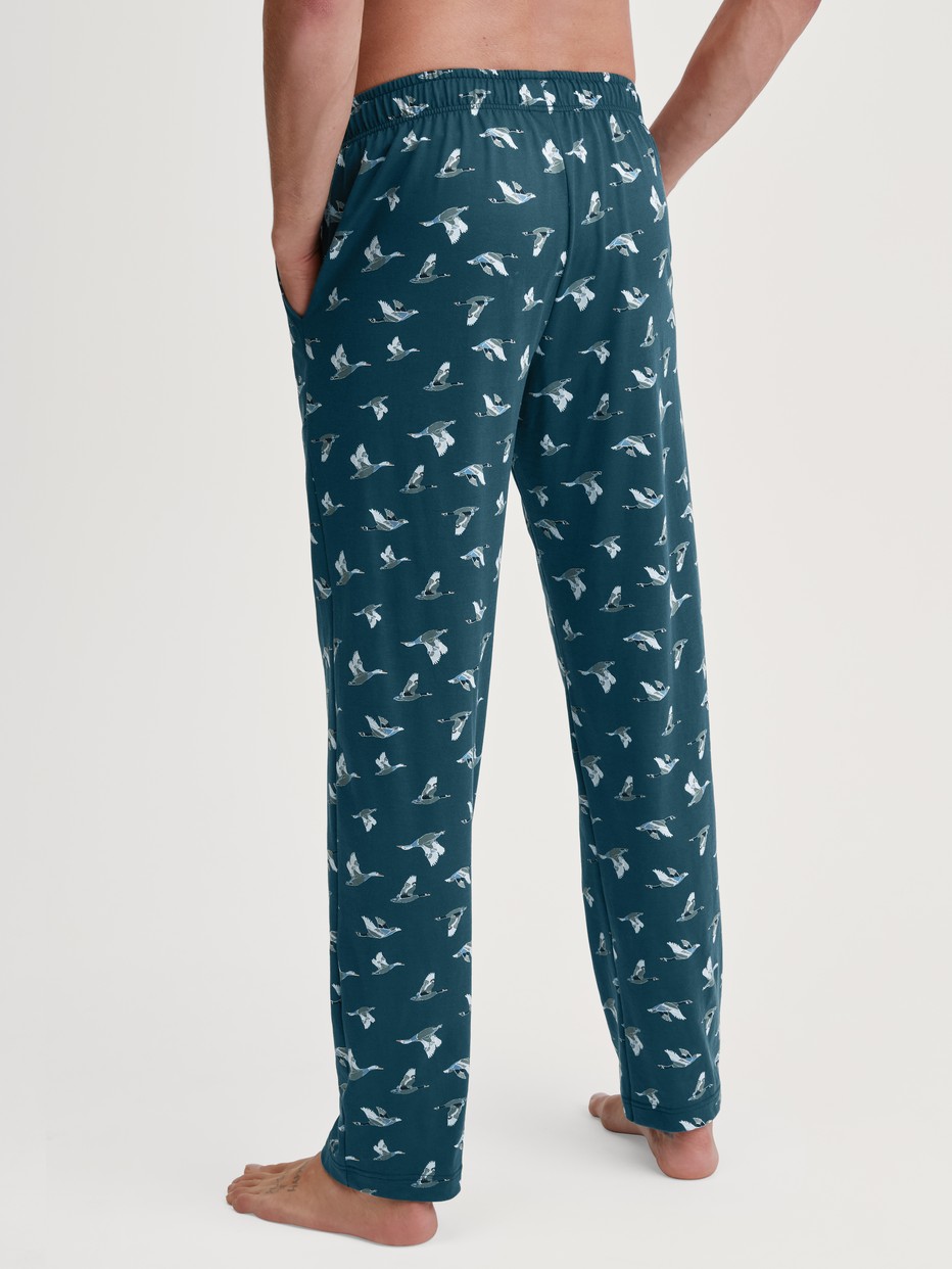 Herren-Model trägt Pyjamahose mit Seitentaschen aus 100% Baumwolle in Grün, Gemustert aus Serie RMX Sleep Weekend von CALIDA, Rückansicht