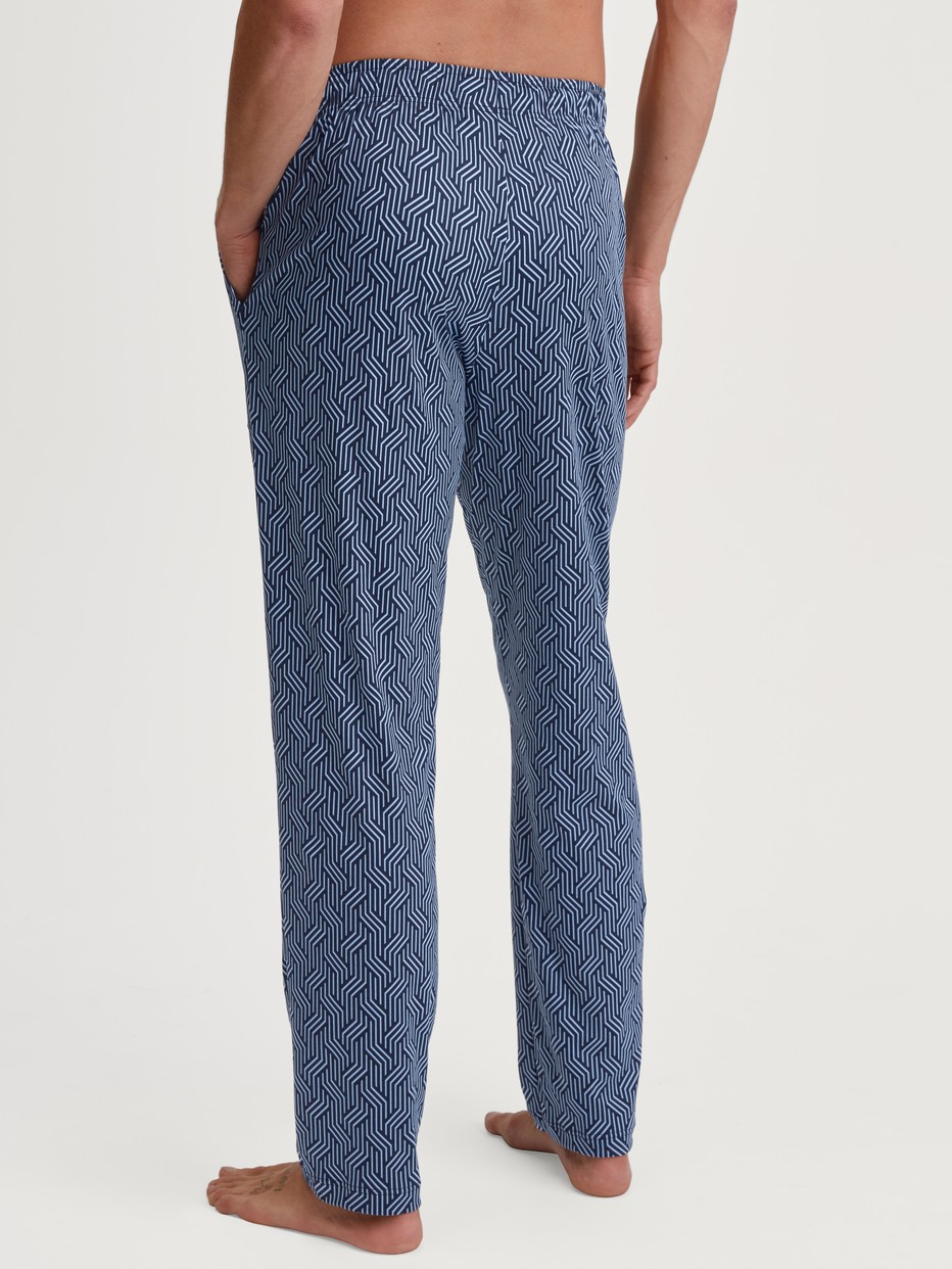 Men model is wearing Pyjama Bottoms with Side Pockets made of Cotton in Blue, Patterned from the RMX Sleep Free series by CALIDA, Back view