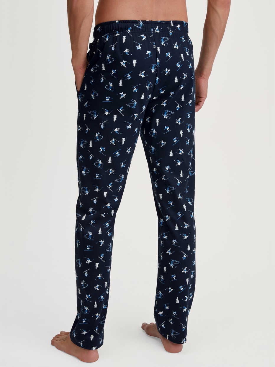 Herren-Model trägt Pyjamahose mit Seitentaschen aus 100% Baumwolle in Blau, Gemustert aus Serie RMX Ski Resort von CALIDA, Rückansicht
