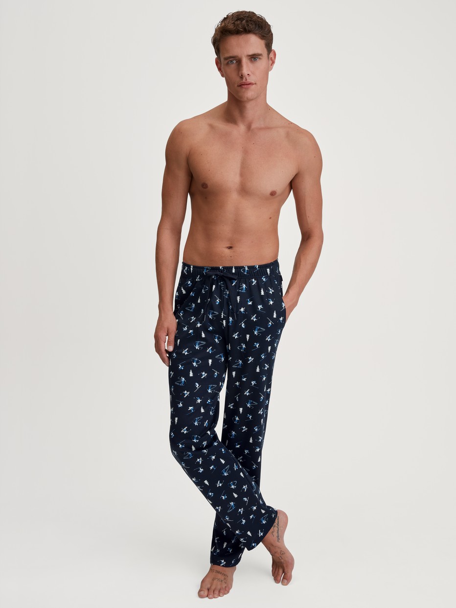 Herren-Model trägt Pyjamahose mit Seitentaschen aus 100% Baumwolle in Blau, Gemustert aus Serie RMX Ski Resort von CALIDA, Outfit