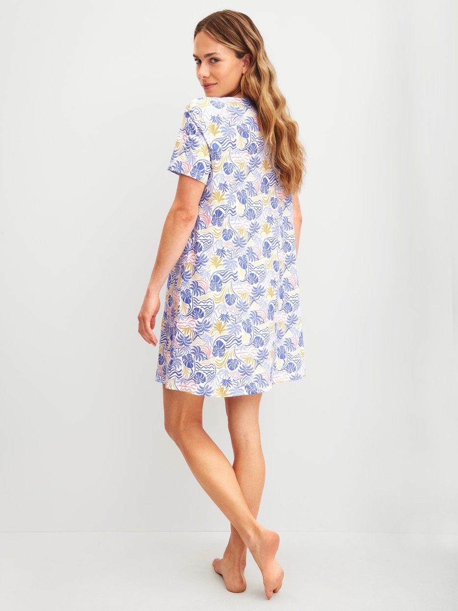 Women model is wearing Short-sleeved nightdress, length 95 cm made of 100% Cotton in Blue, Floral from the Coastal Dreams series by CALIDA, Back view