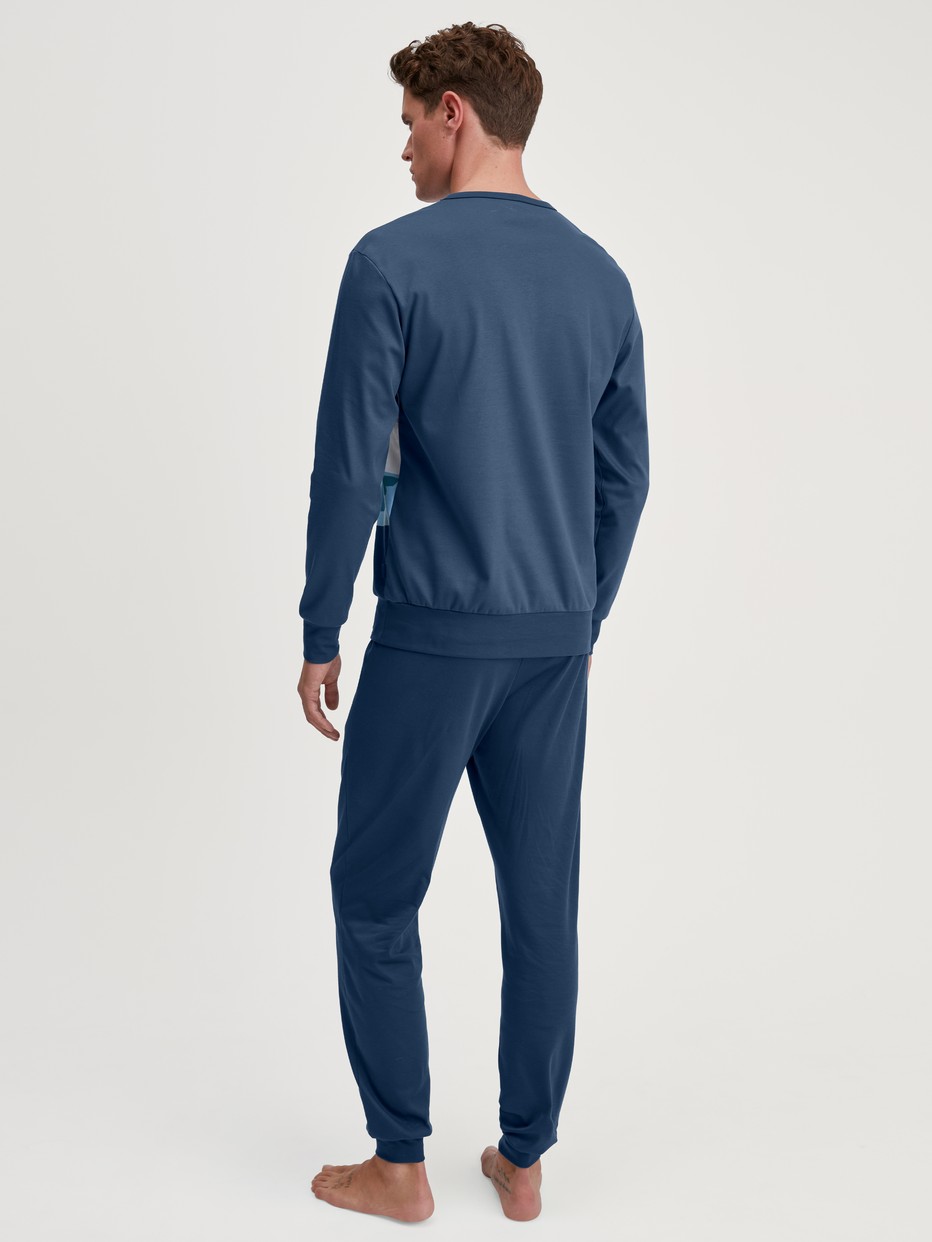 Herren-Model trägt Bündchen-Pyjama aus 100% Baumwolle in Blau, Motiv aus Serie Relax Ski Resort von CALIDA, Rückansicht