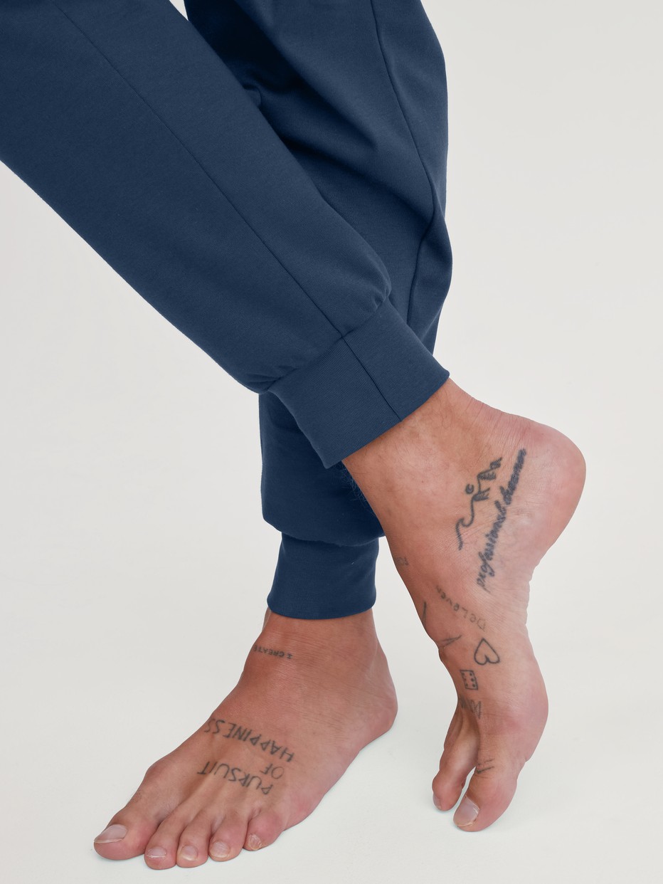 Herren-Model trägt Bündchen-Pyjama aus 100% Baumwolle in Blau, Motiv aus Serie Relax Ski Resort von CALIDA, Detail