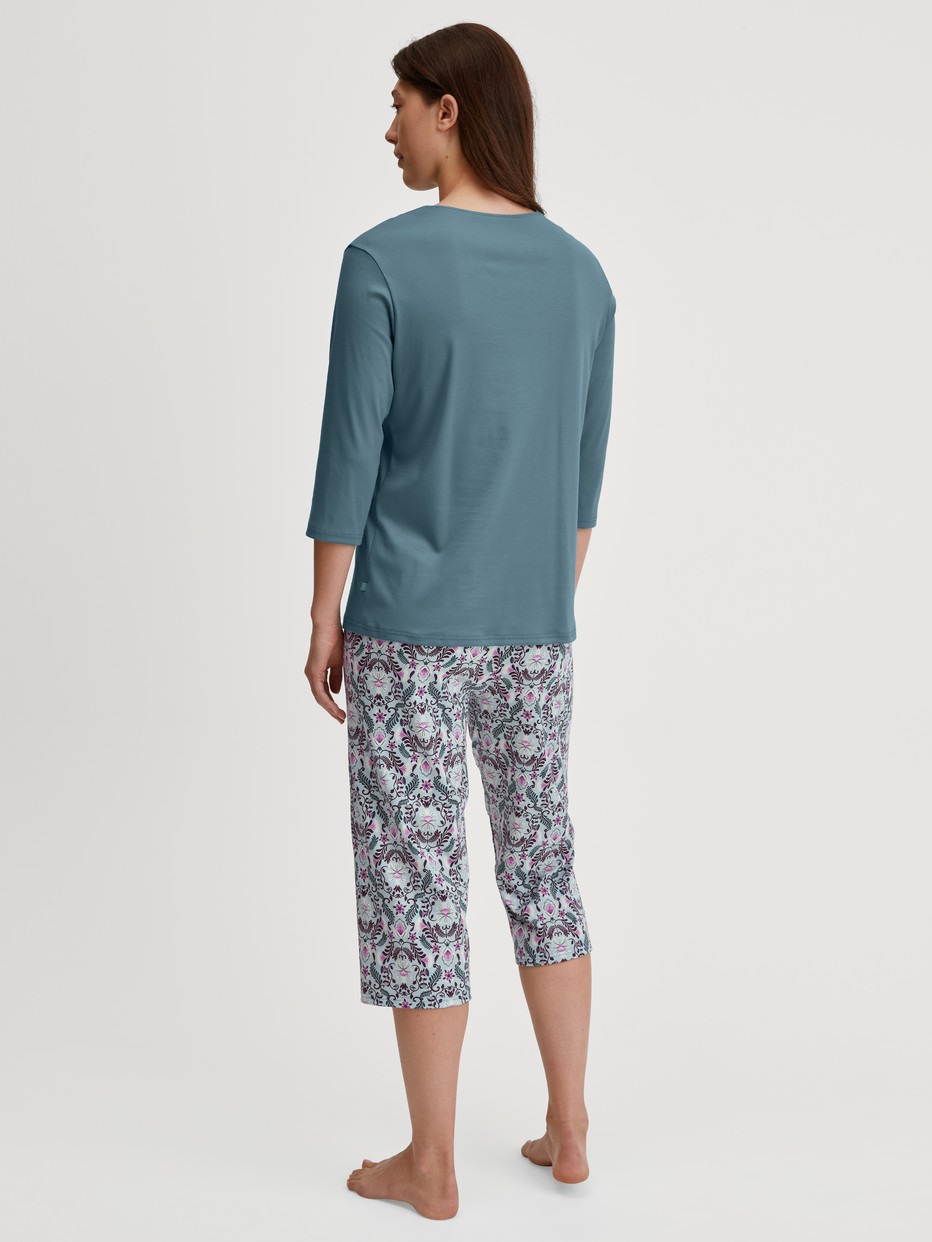 Women model is wearing Capri Pyjama made of 100% Cotton in Blue, Patterned from the Autumn Dreams series by CALIDA, Back view