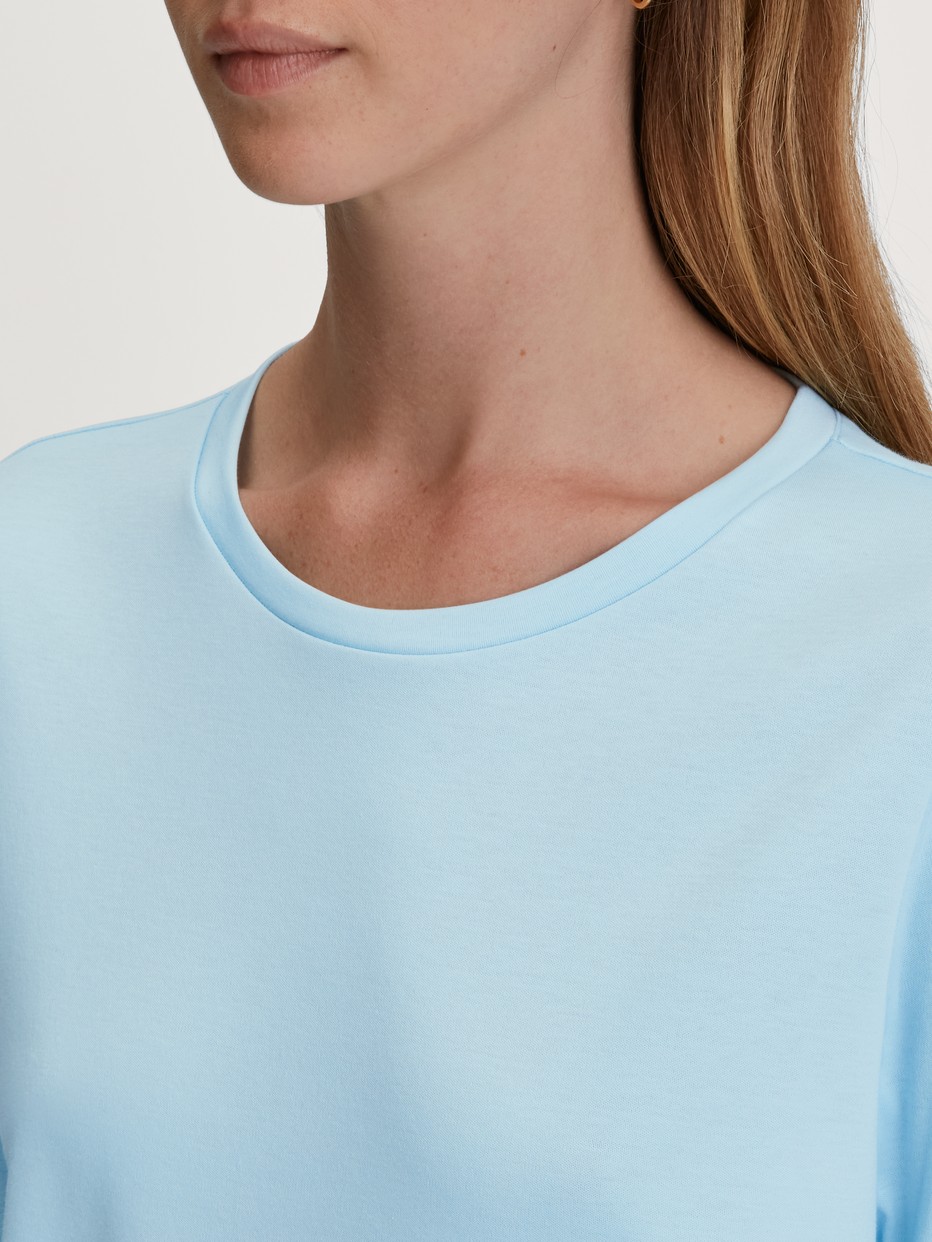 La modella / Il modello Donna indossa Pigiama con polsini in 100% cotone di colore Blu, Modello, della serie Swiss Resort di CALIDA, Dettaglio