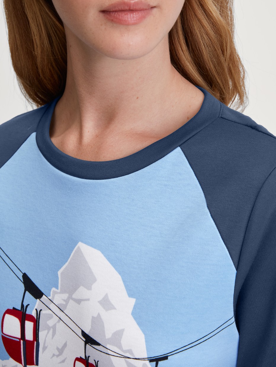 Damen-Model trägt Bündchen-Pyjama aus 100% Baumwolle in Blau, Motiv aus Serie Ski Resort von CALIDA, Detail