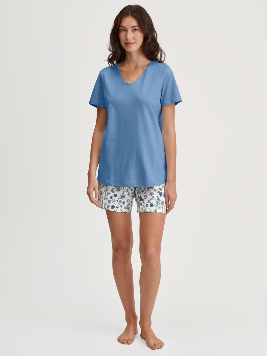 Damen-Model trägt Kurz-Pyjama aus 100% Baumwolle in Blau, Floral aus Serie Flower Nights von CALIDA, Vorderansicht