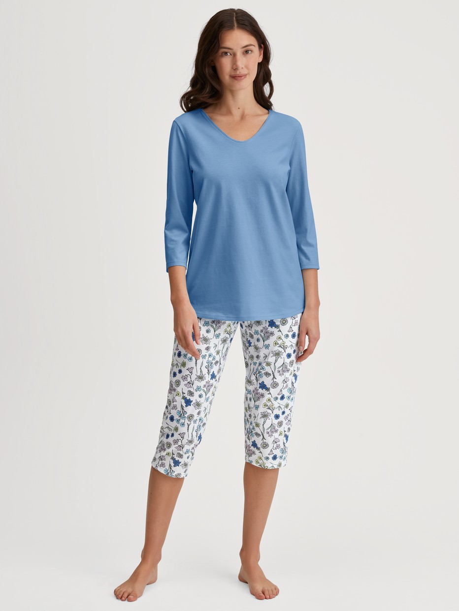 La modella / Il modello Donna indossa Pigiama capri in 100% cotone di colore Blu, Floreale, della serie Flower Nights di CALIDA, Vista frontale
