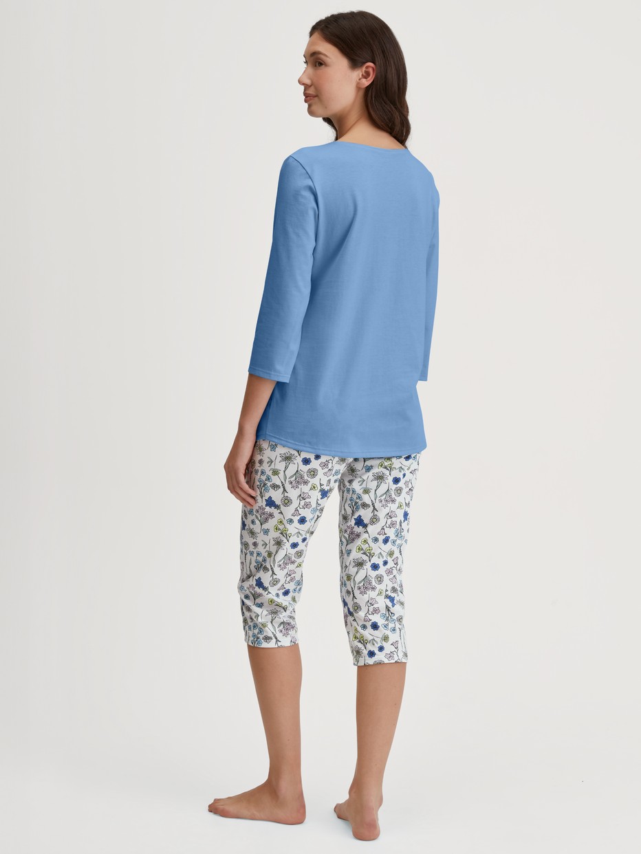 La modella / Il modello Donna indossa Pigiama capri in 100% cotone di colore Blu, Floreale, della serie Flower Nights di CALIDA, Vista posteriore