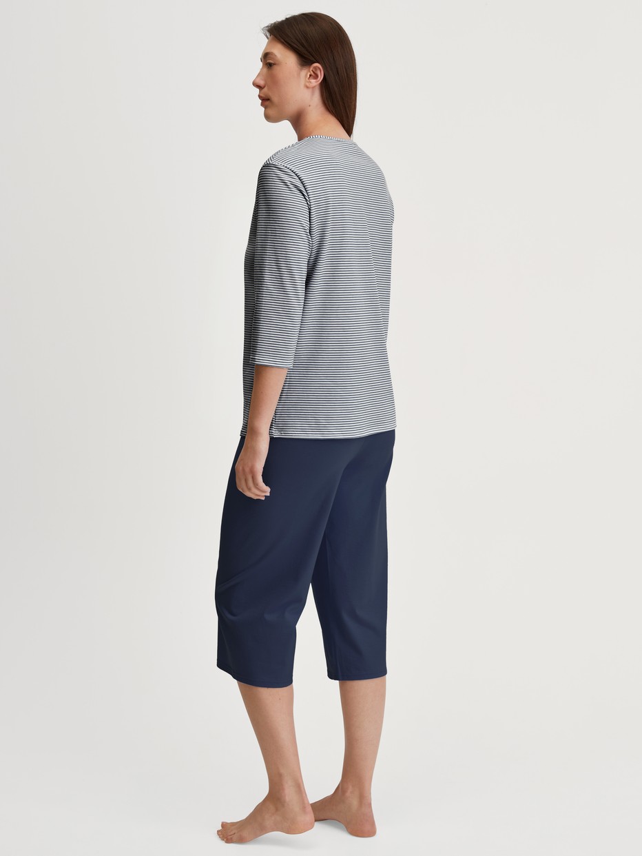 Women model is wearing Capri Pyjama made of 100% Cotton in Blue, Patterned from the Cotton Special series by CALIDA, Back view