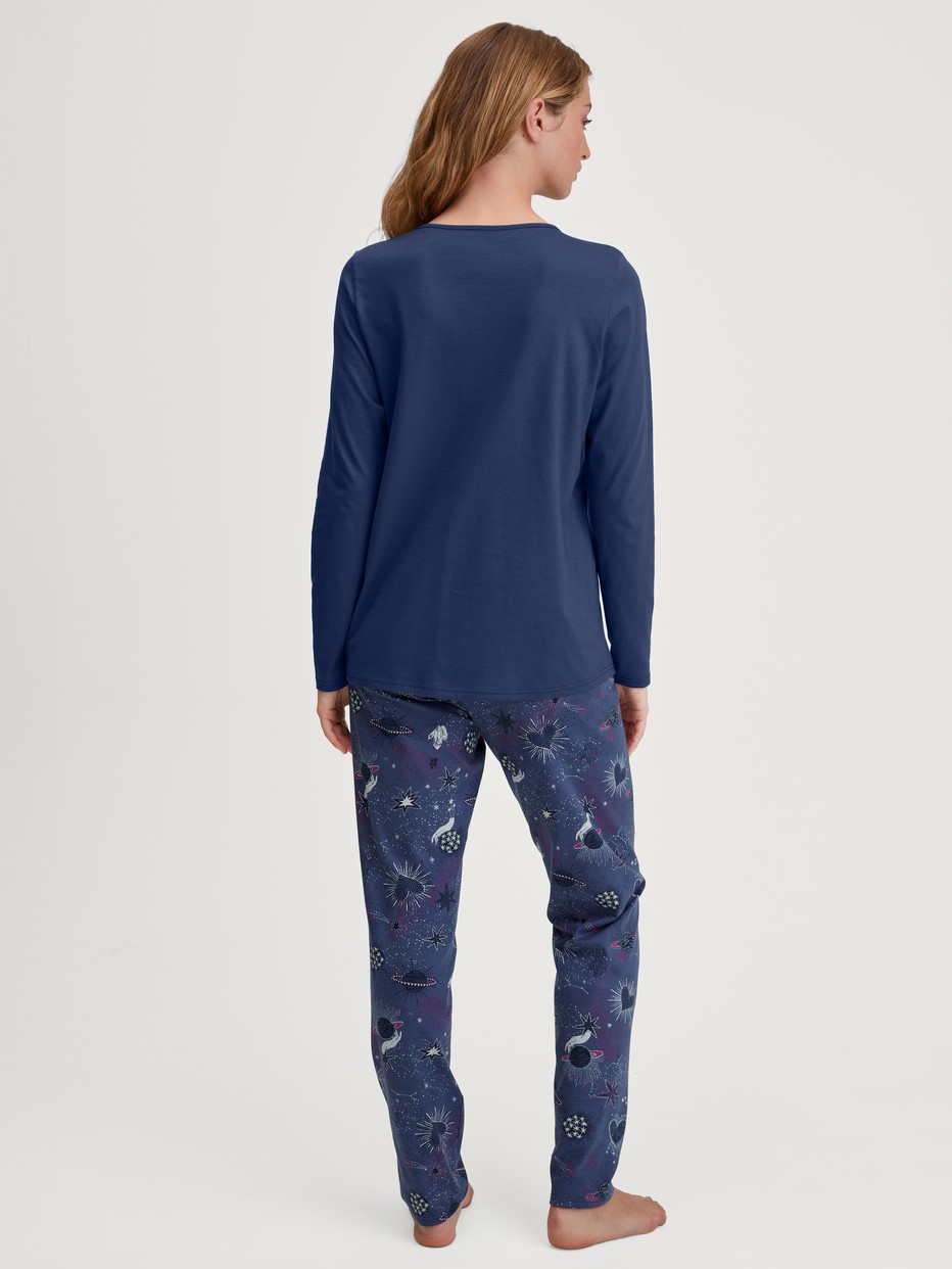 Women model is wearing Pyjamas, long made of 100% Cotton in Blue, Patterned from the Mystic Nights series by CALIDA, Back view