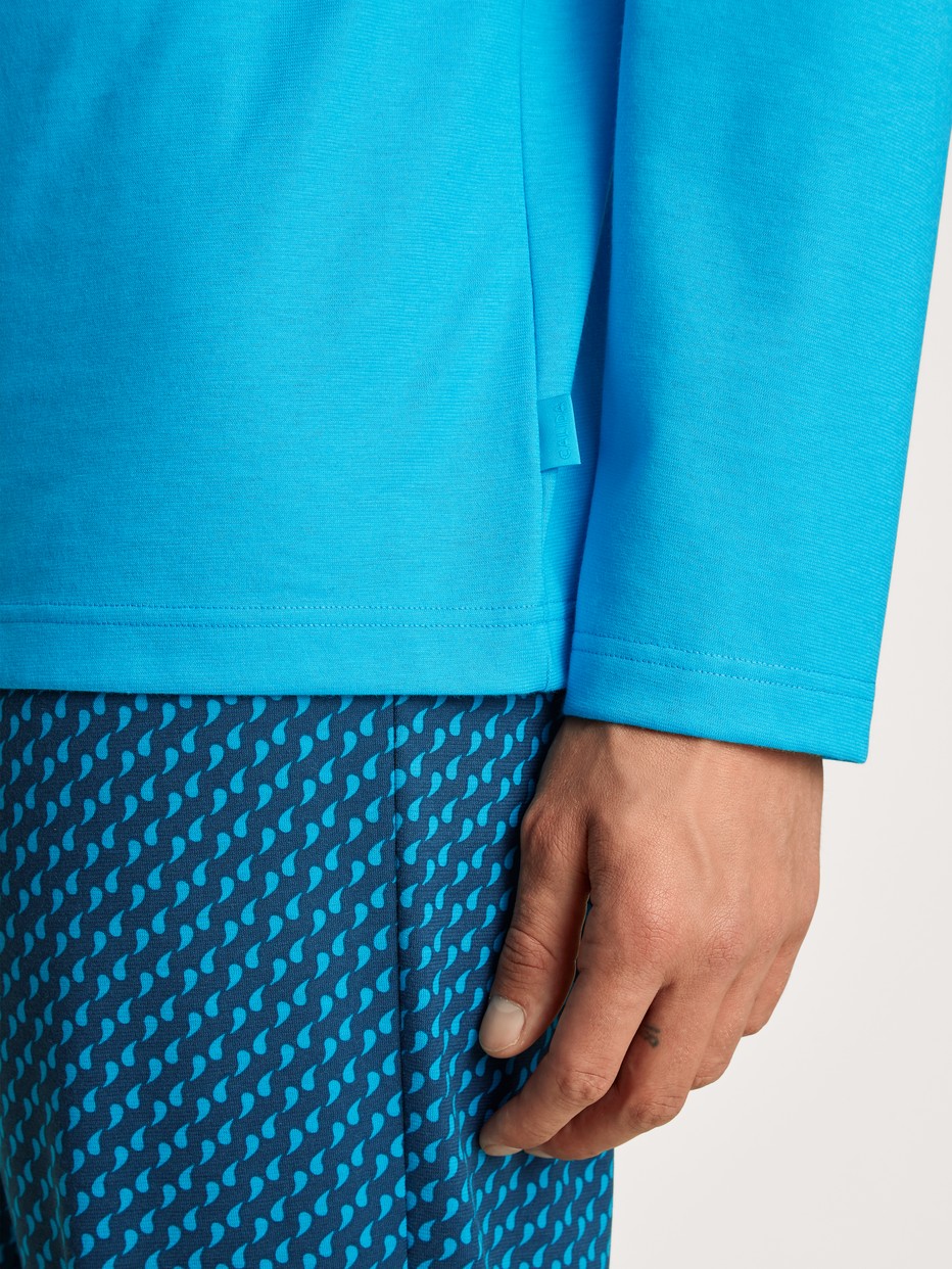 Herren-Model trägt Pyjama, lang aus 100% Baumwolle in Türkis, Motiv aus Serie Relax Imprint 1 von CALIDA, Detail