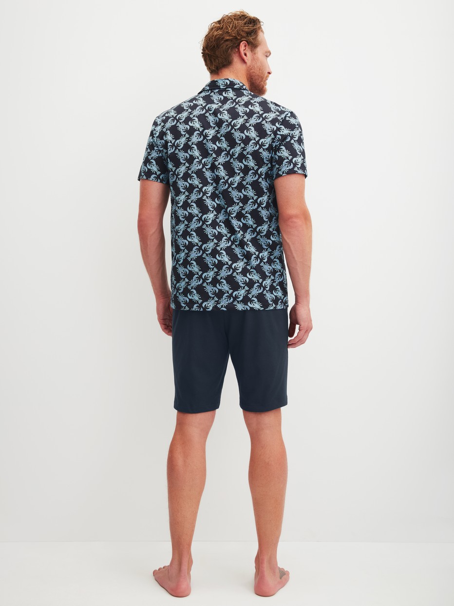 Herren-Model trägt Kurz-Pyjama aus 100% Baumwolle in Blau, Gemustert aus Serie Relax Imprint 2 von CALIDA, Rückansicht