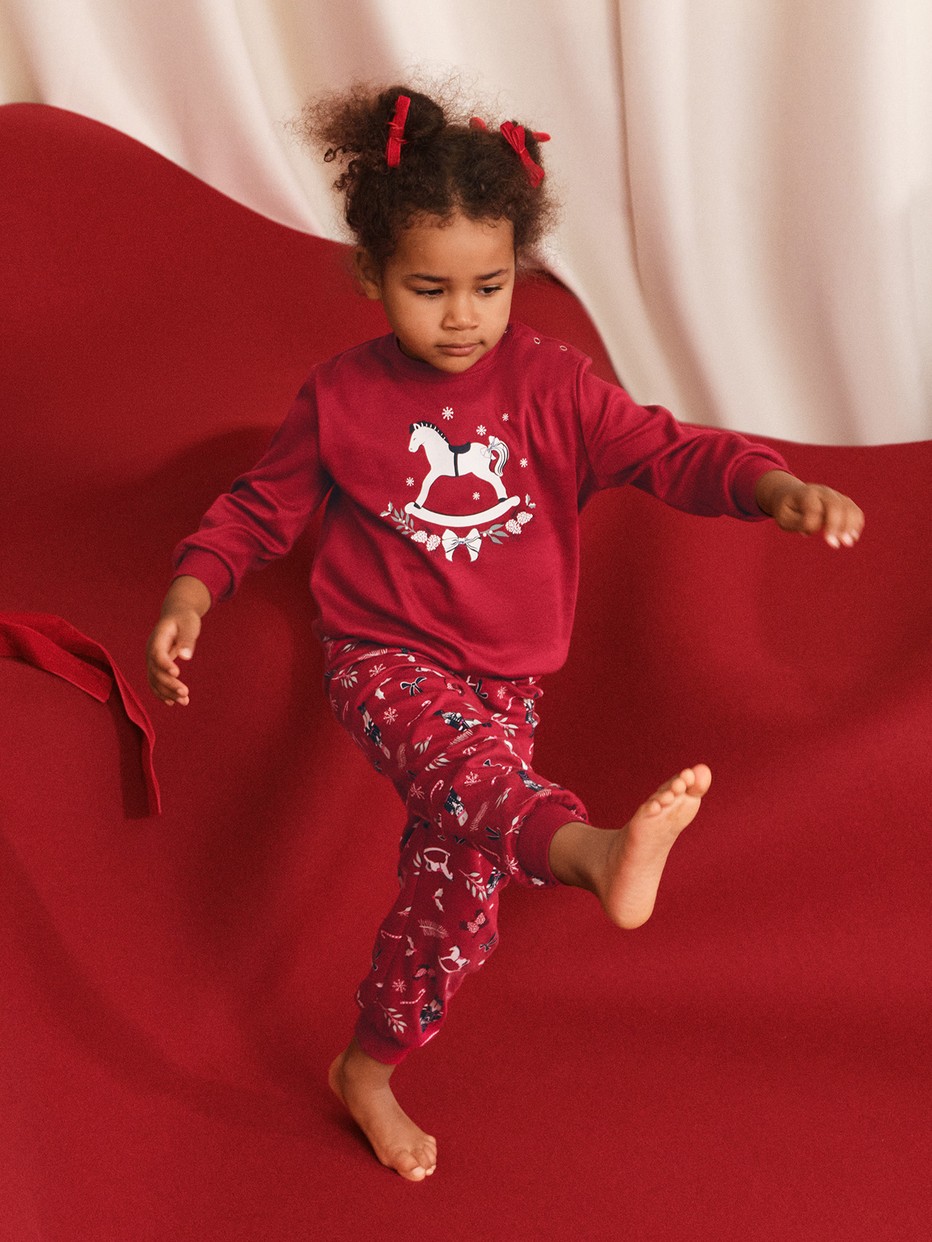 Kids model is wearing Pyjama with cuff made of 100% Cotton in Red, Patterned from the Family & Friends series by CALIDA, Front view